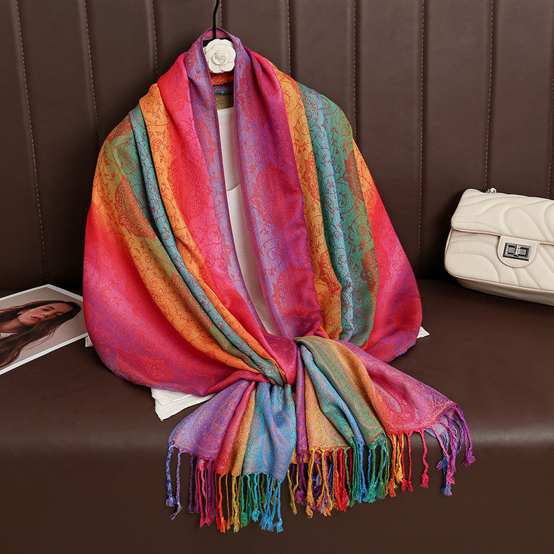 HueWrap rainbow paisley scarf draped on a hanger with tasseled ends