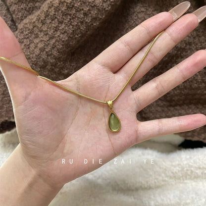 DewLume green teardrop pendant on a gold-tone chain resting across an open palm