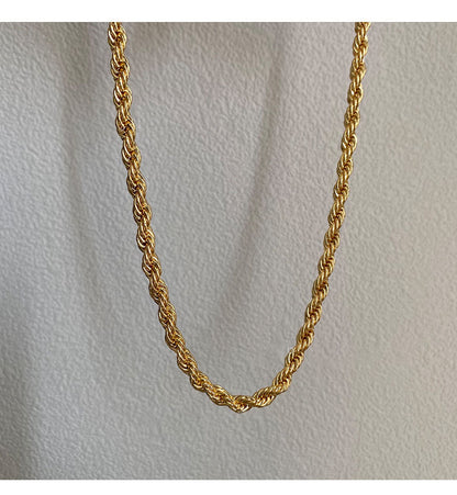 AuriTwist gold-tone twisted rope chain displayed against a cream wall