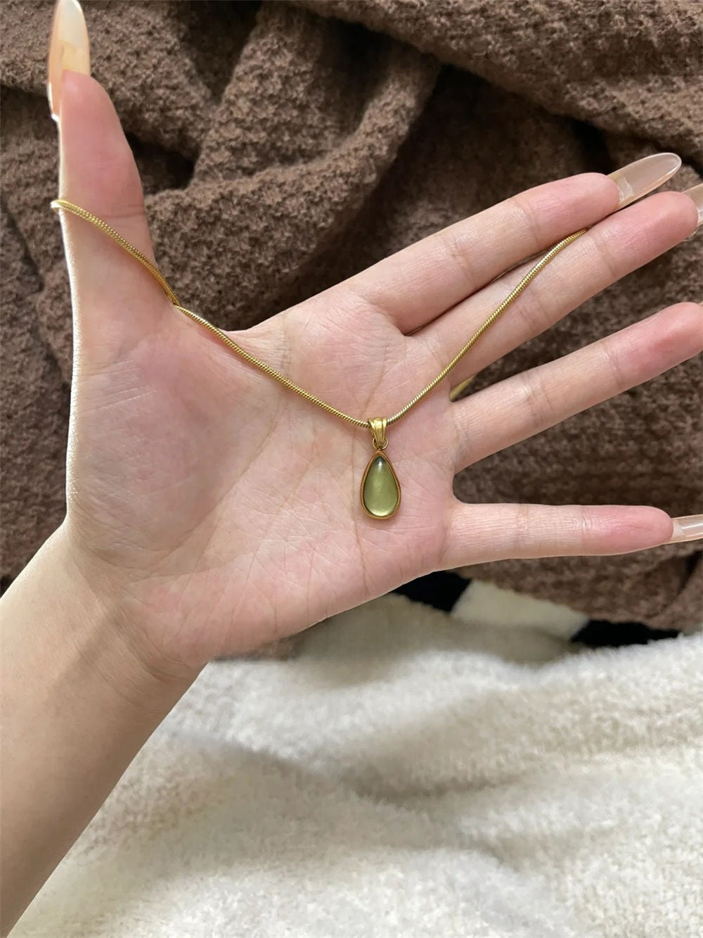 DewLume green pendant shown from another angle in hand with its gold-tone chain