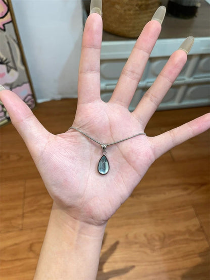 DewLume blue teardrop pendant necklace resting in an open hand to show its shape