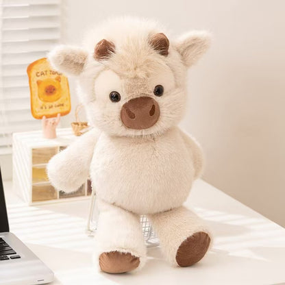 CreamCuddle Highland cow plush sitting on a desk with cream fur, brown snout and matching hooves
